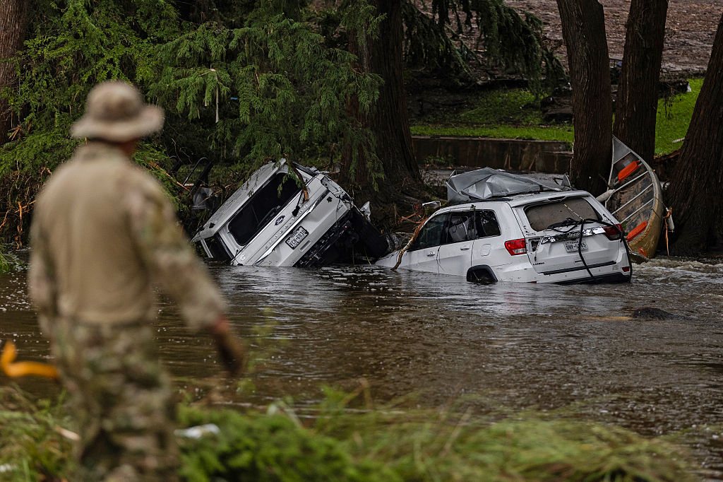 HUNT, TEXAS - JULY 6: Vehicles sit submerged as a search and rescue worker looks through debris for any survivors or remains of people swept up in the flash flooding on July 6, 2025 in Hunt, Texas. Heavy rainfall caused flooding along the Guadalupe River in central Texas with multiple fatalities reported.