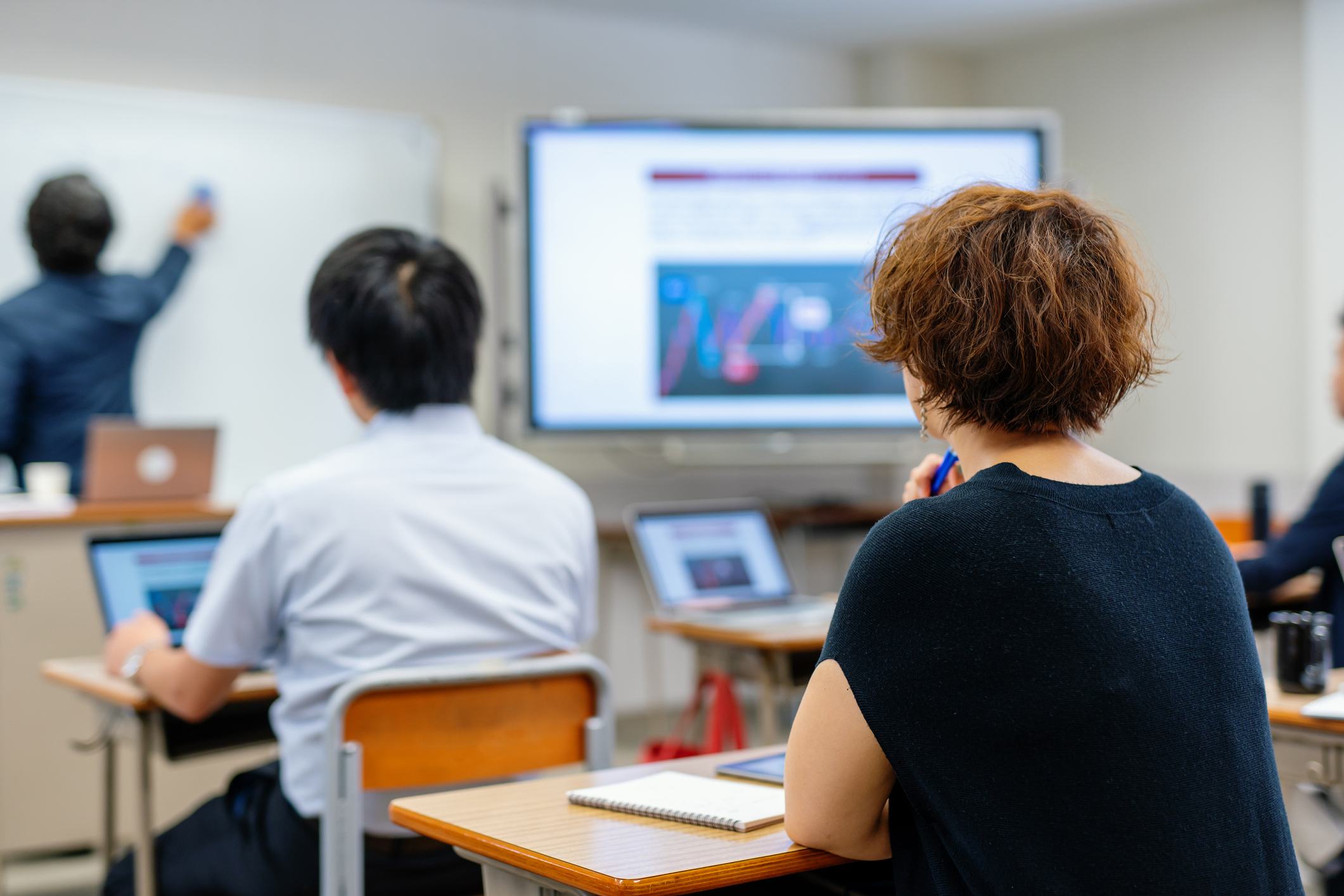 Mid adult woman in a team training class with an instructor at the board