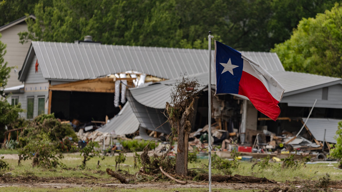 A Texas state flag flies in a yard filled with debris on July 6, 2025 in Hunt, Texas