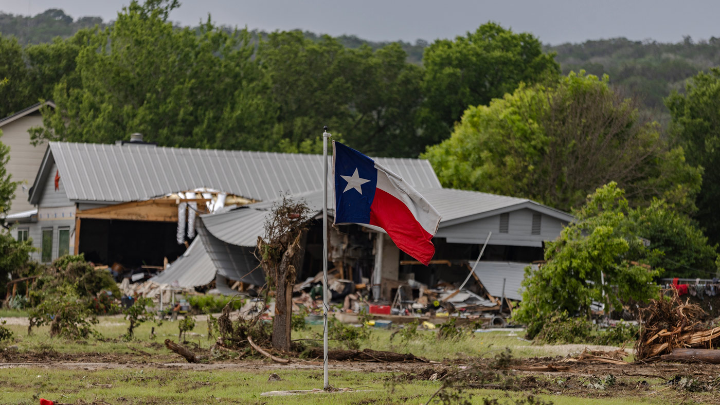 A Texas state flag flies in a yard filled with debris on July 6, 2025 in Hunt, Texas.