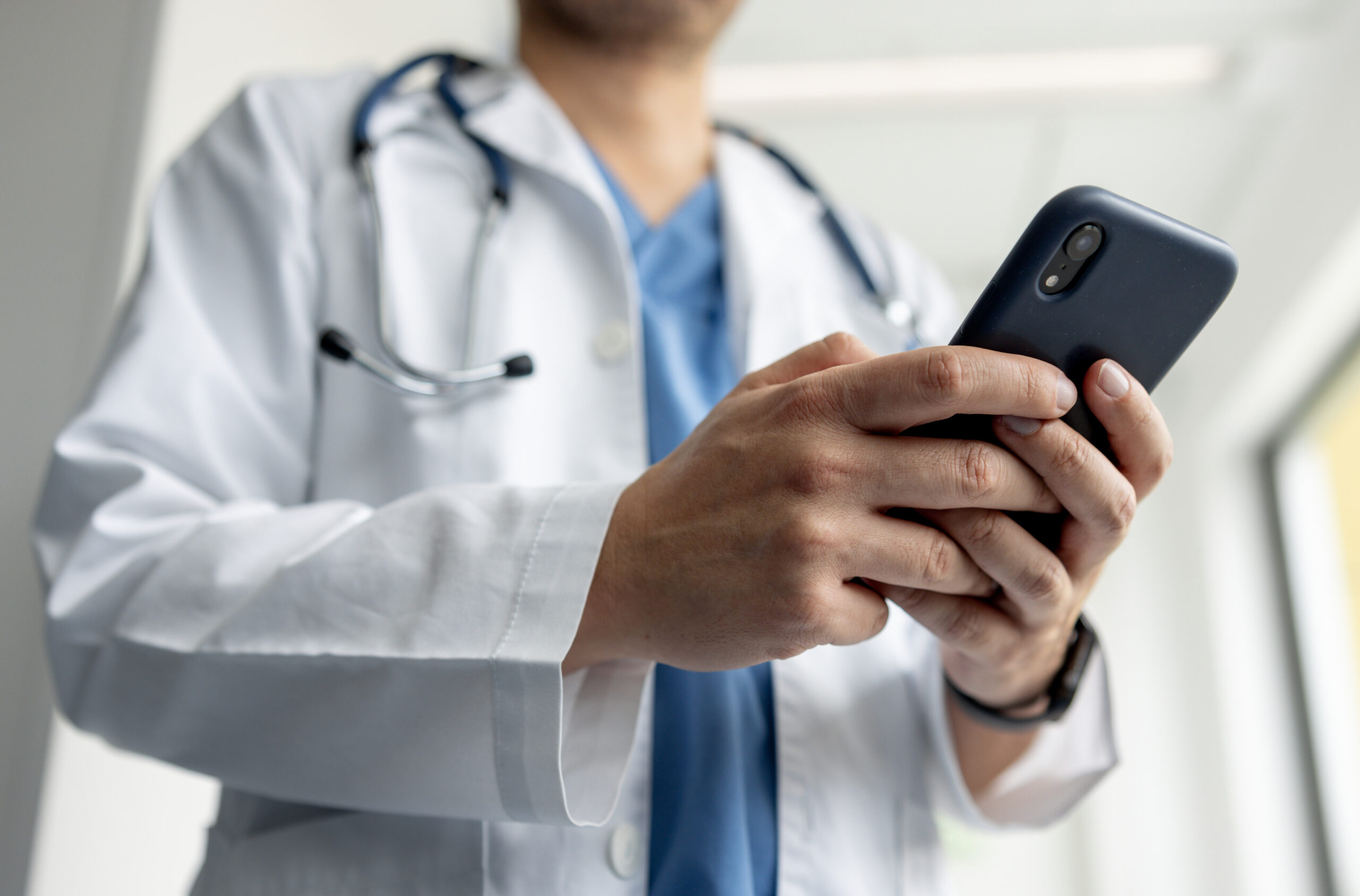 Close-up photo of a doctor texting on his cell phone while working at the hospital.