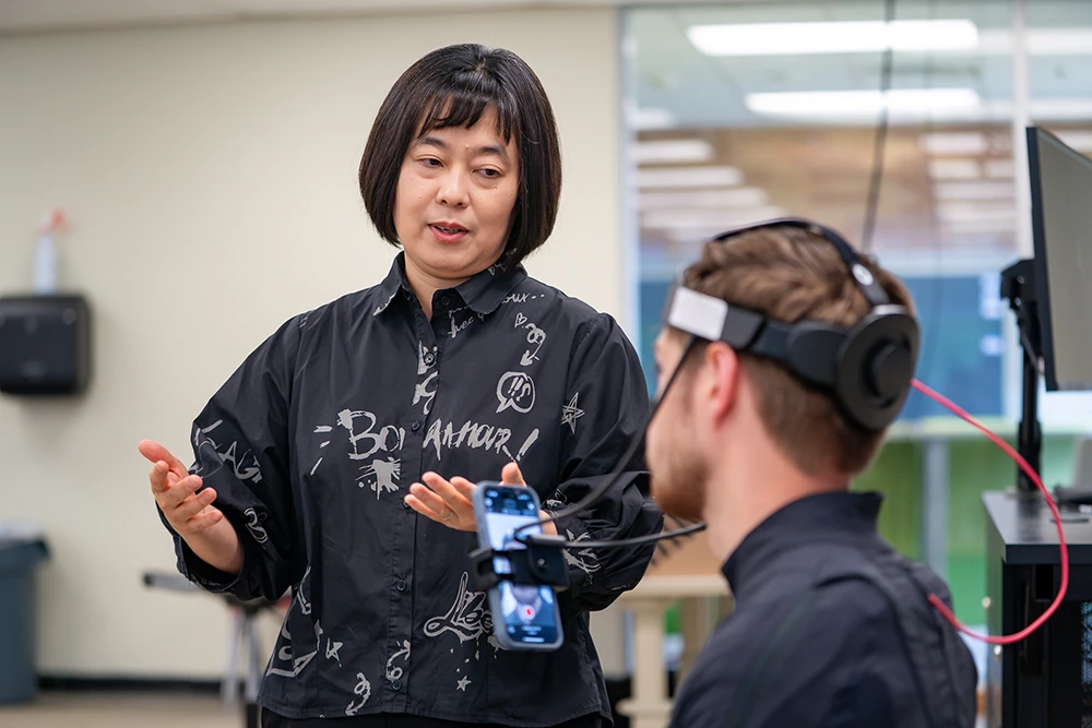 Dr. Seo talking to a student in motion capture equipement