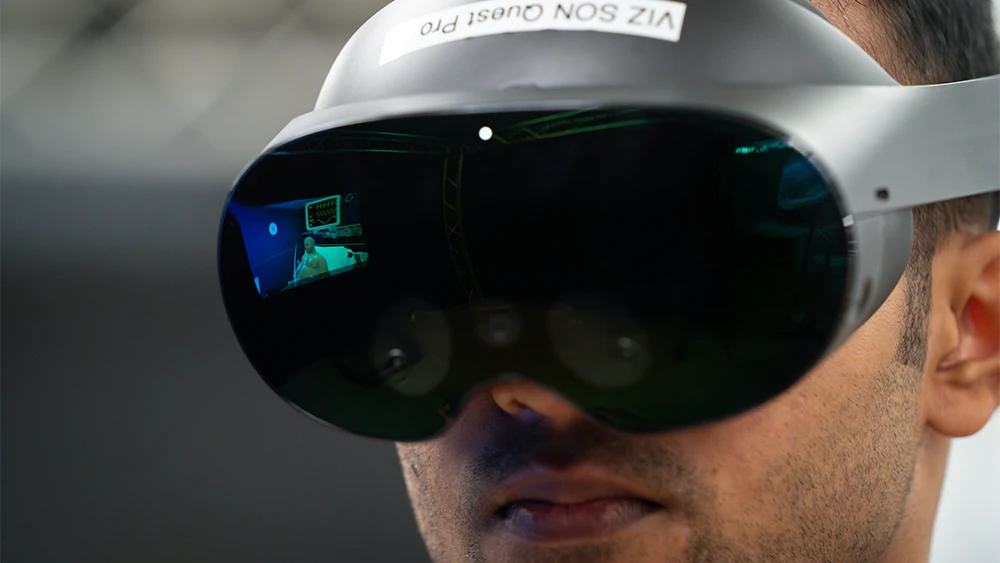 Close up of a student wearing a VR headset with a reflection of what he sees in the glass
