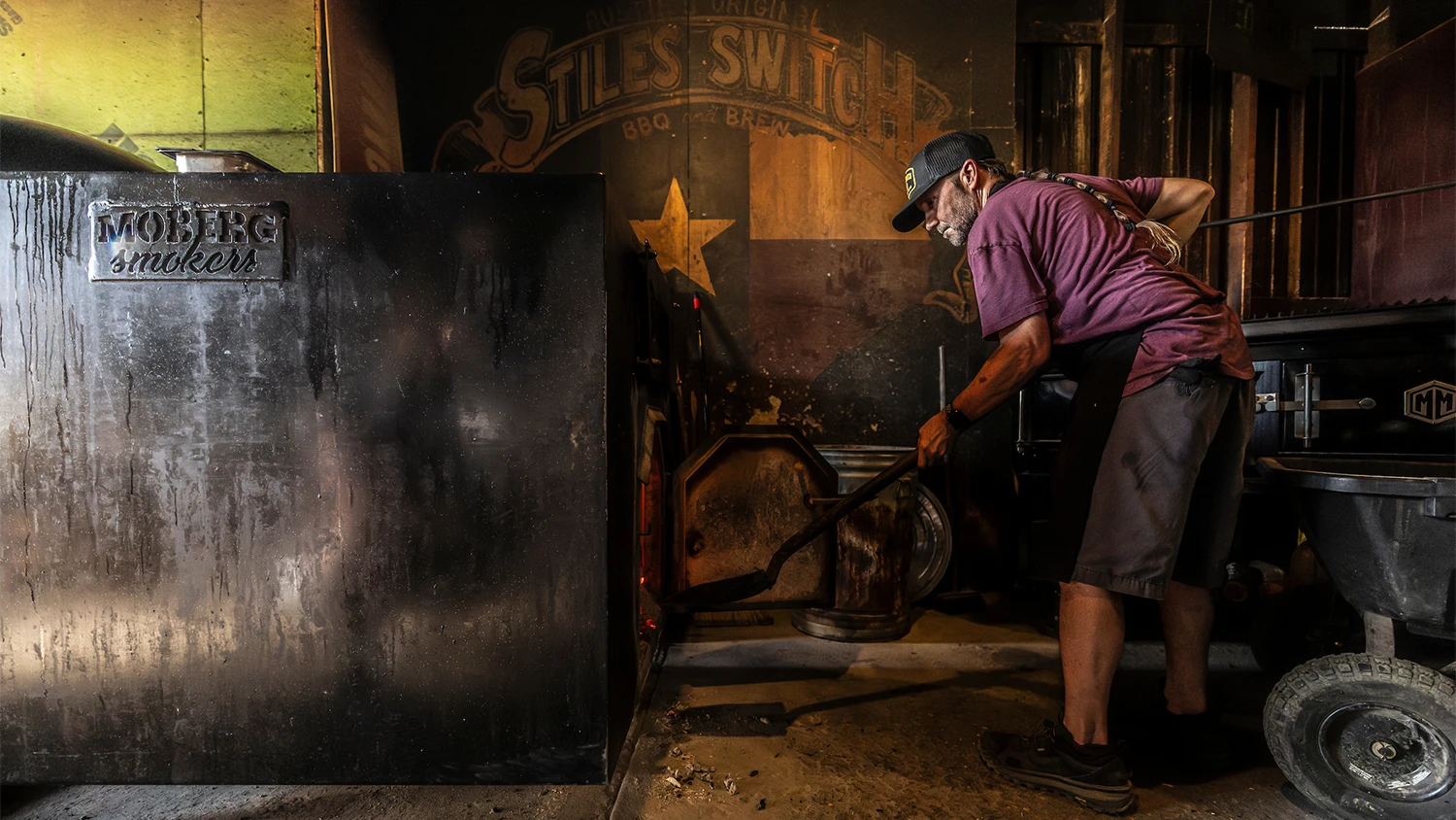 A pit master at Styles Switch BBQ stokes the fire in the smoker