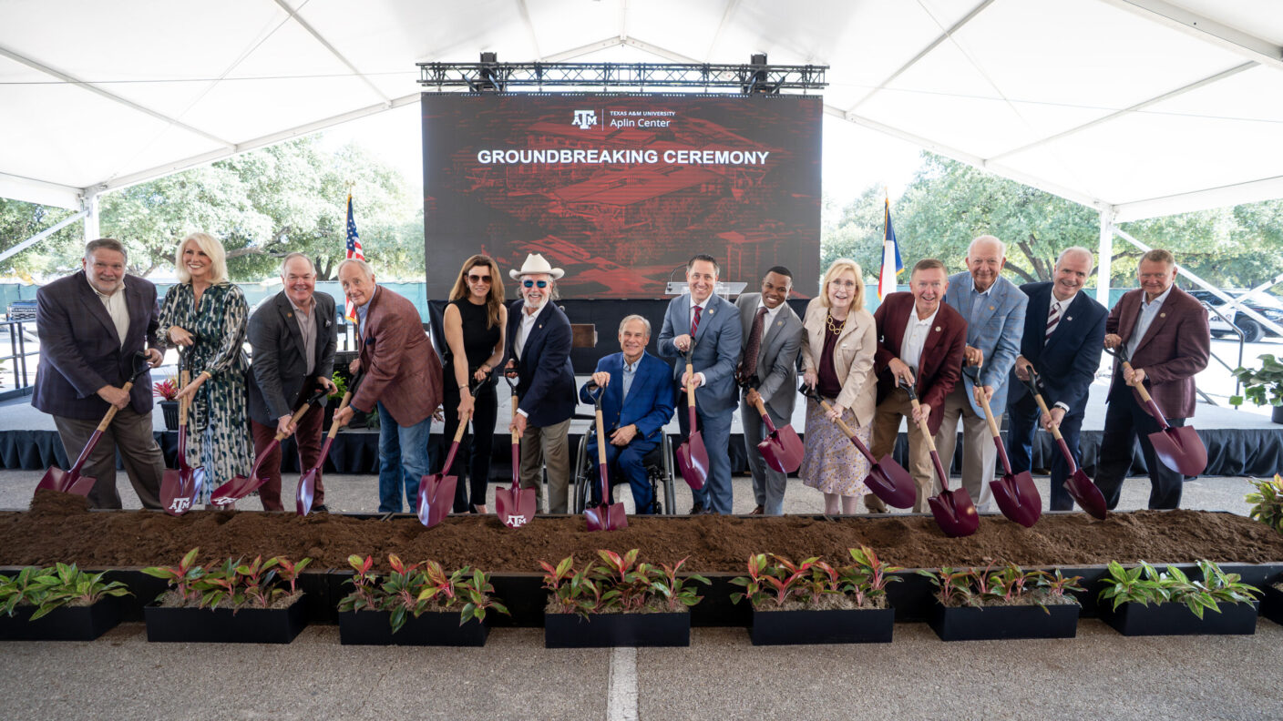 A photo of people at a groundbreaking ceremony standing with shovels over a pile of dirt.