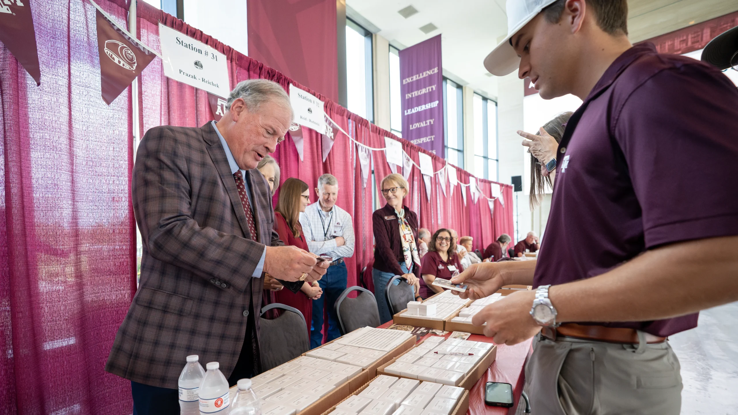 Interim President Tommy Williams '78 handing a ring to an Aggie student on ring day