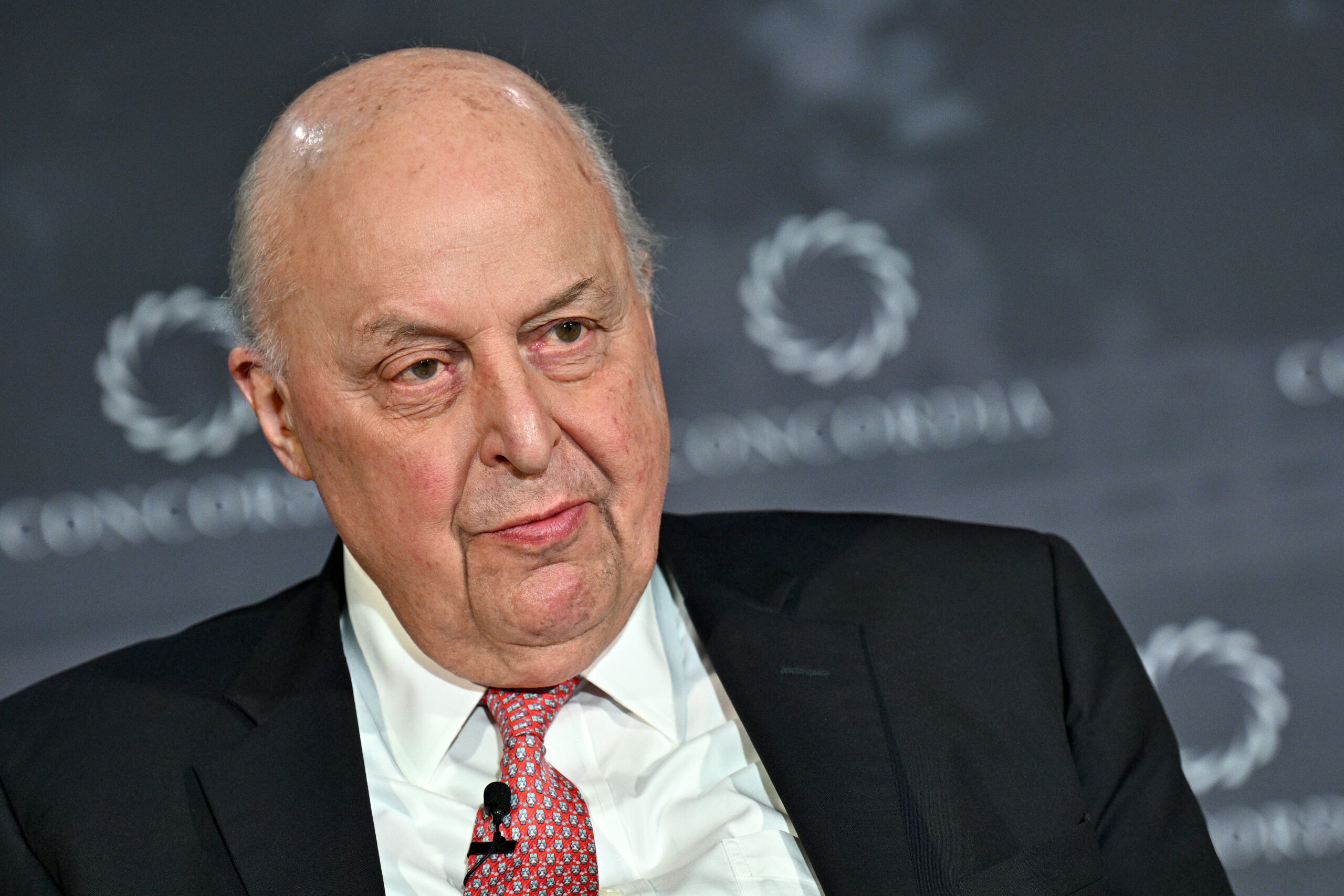 A photo of a man in a suit on a stage during an event.