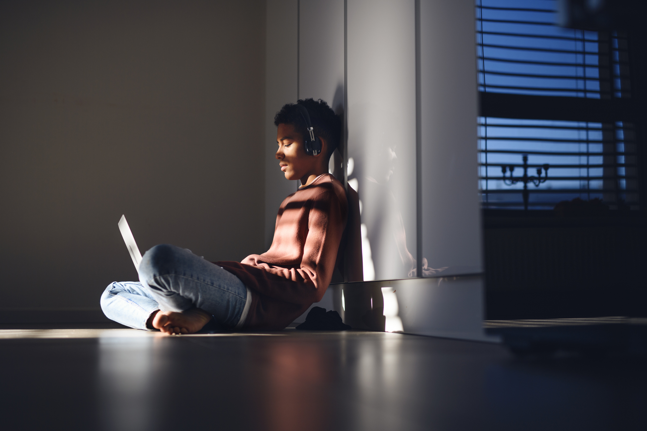 a teenager using a laptop and wearing headphones
