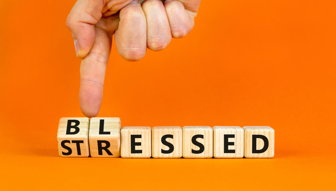 Wooden blocks that spell out the word stressed, with a finger turning over the first two blocks to expose new letters to make the word blessed.