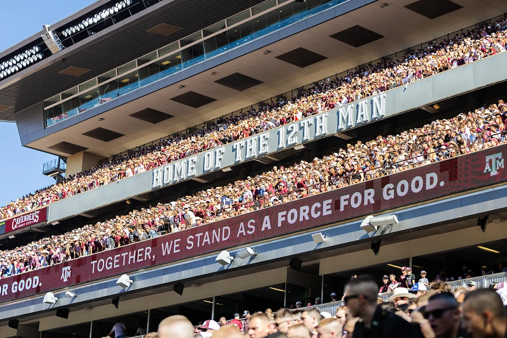 The packed Kyle Field stands emblazoned with "Home of the 12th Man" and "Together, we stand as a force for good."