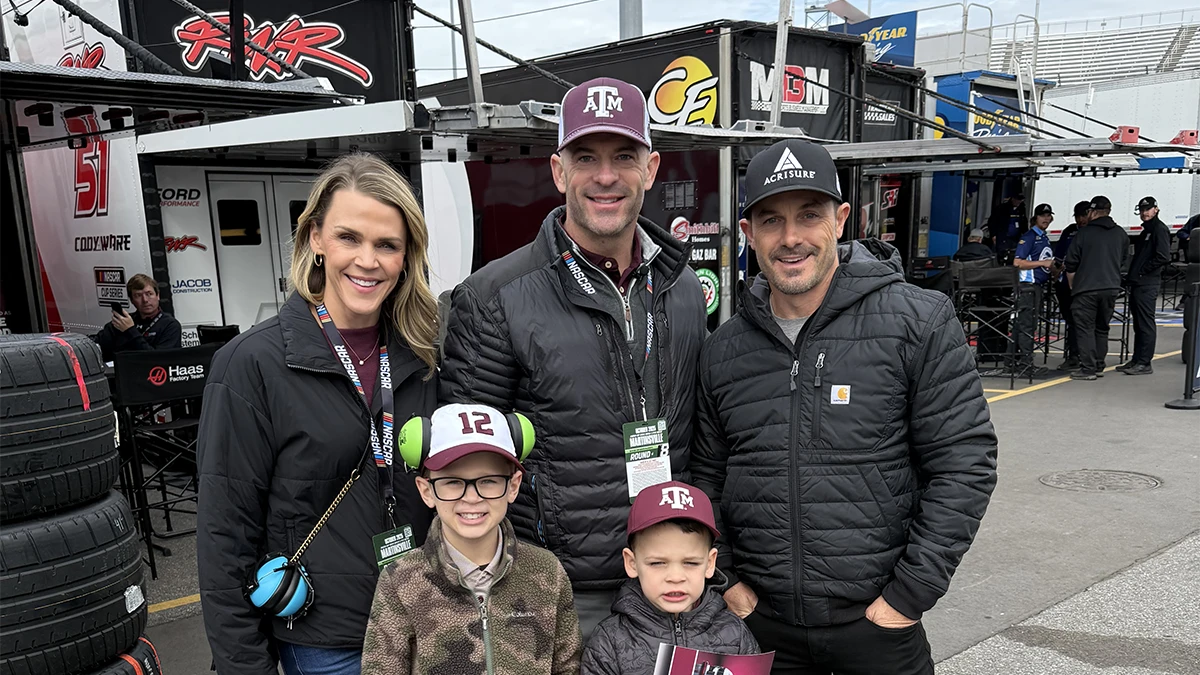 Matt Williams and his family pose on the NASCAR track wearing Aggie gear