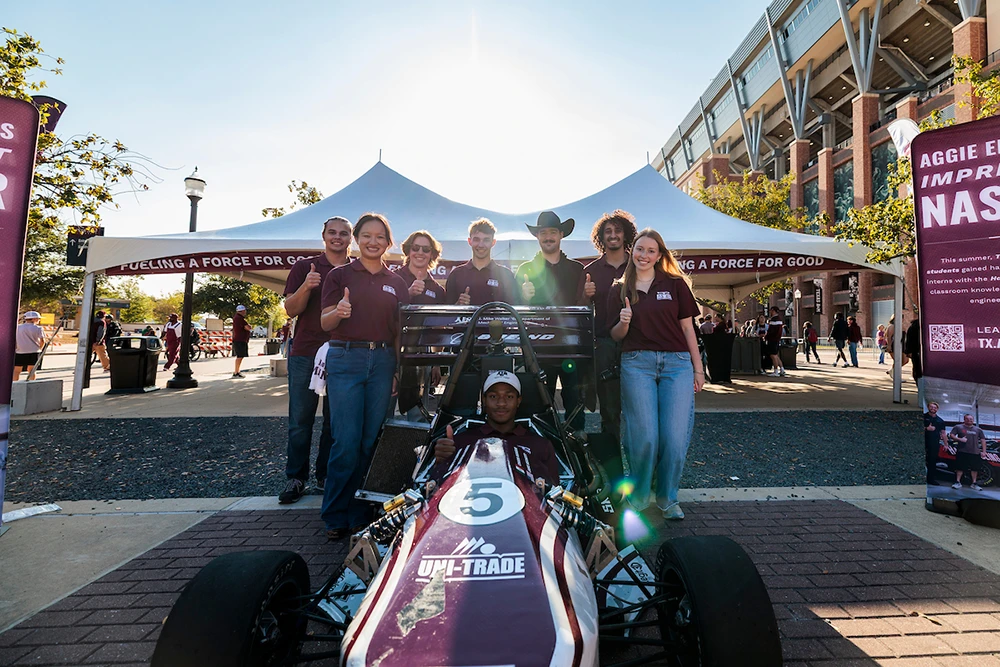 The Texas A&M FSAE team poses behind their racecar outside of Kyle Field.