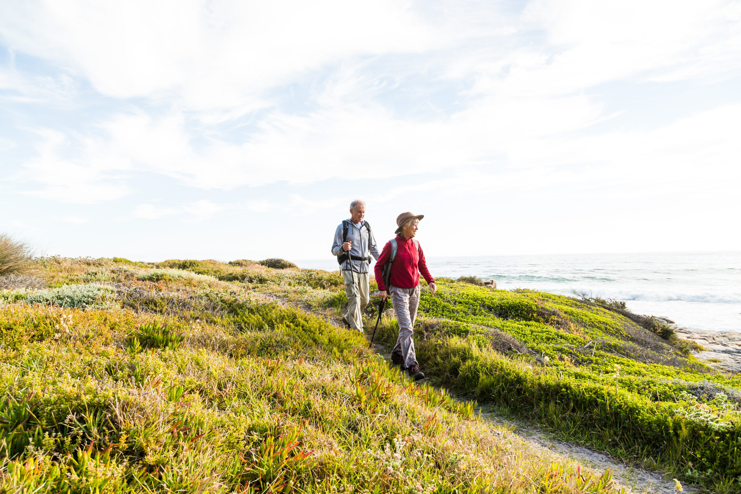 A photo of an older couple hiking together on a coastal path.