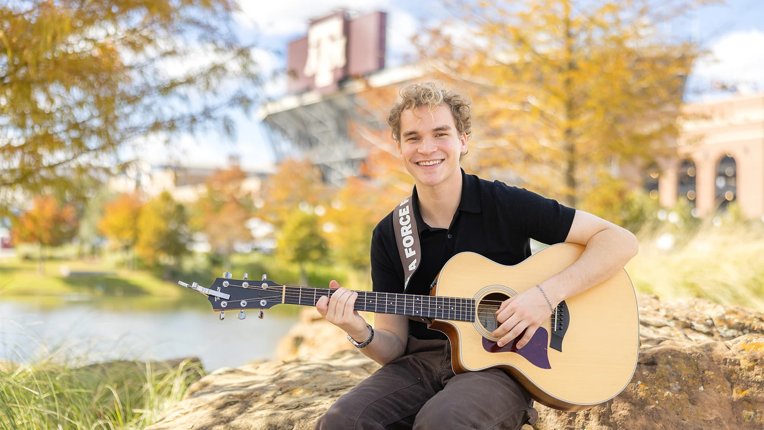 Portrait of Aiden Ross holding his acoustic guitar in Aggie Park