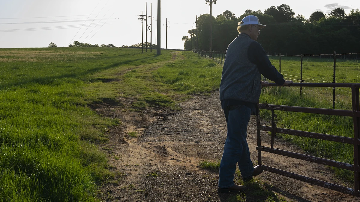 A farmer opening a gate to a pasture