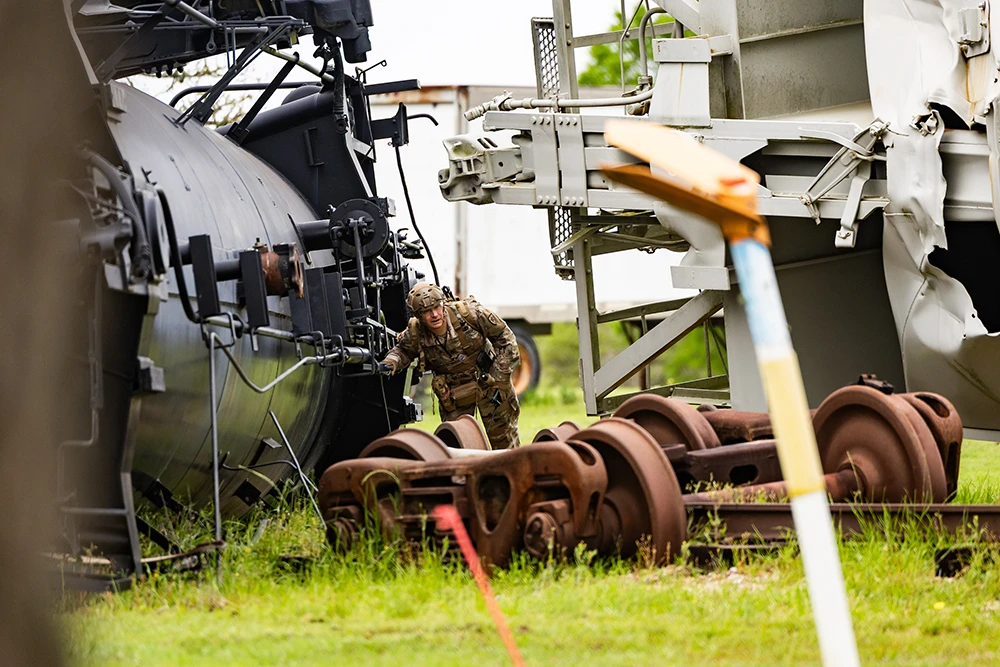 Person in combat fatigues climbs through train wreckage