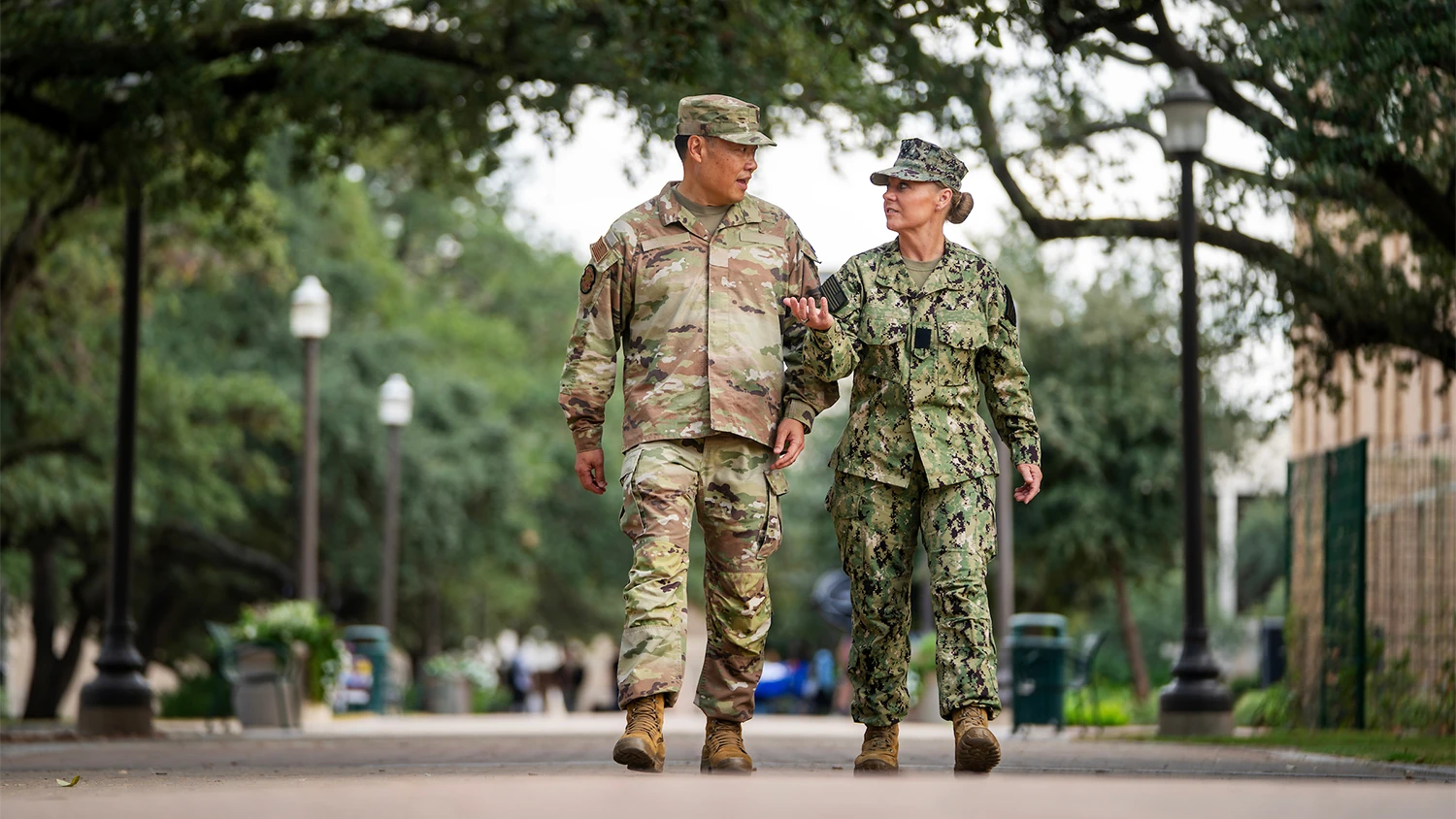 Two veterans in military fatigues talk together while walking down Military Walk