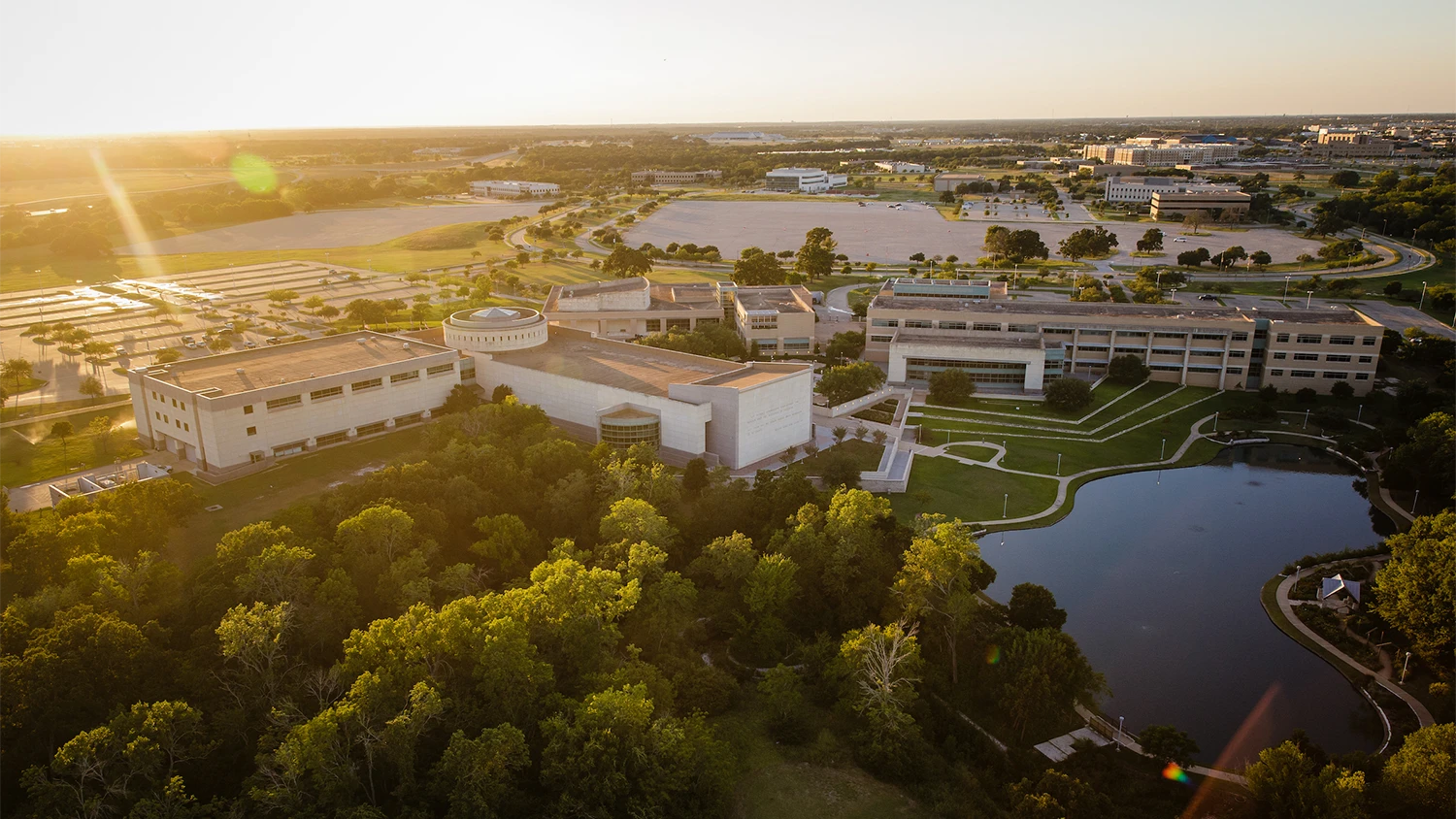 Aerial view of a small lake and a wooded area next to the Bush School buildings