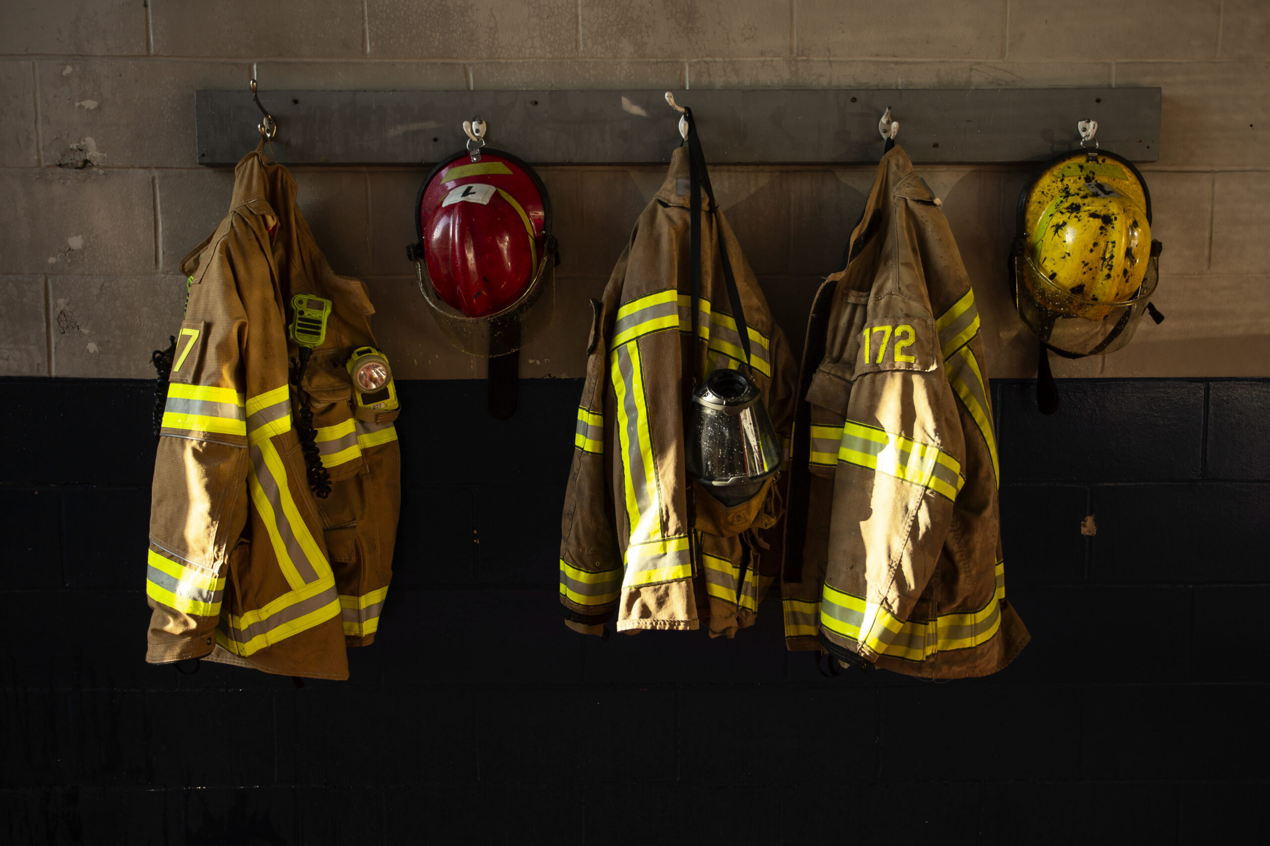 Firefighter protective gear hanging on a wall at a fire station.