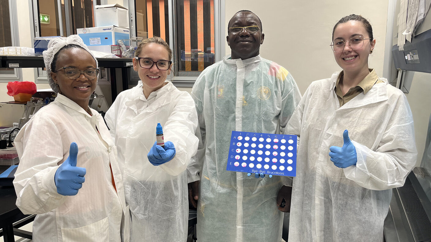 A photo of four people in a lab wearing protective garments.
