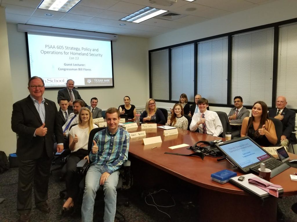 Students and faculty posing around boardroom table