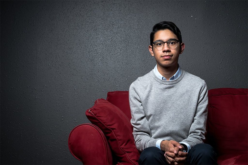 Gonzales sitting on red couch