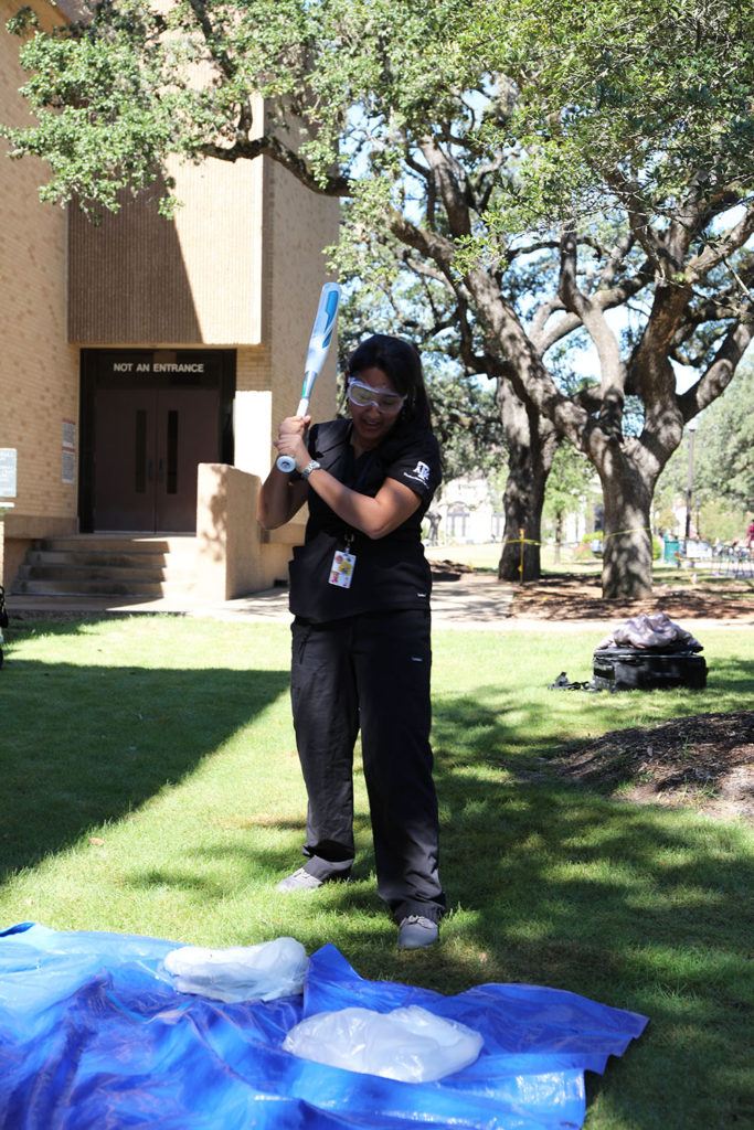 a student holds a bat and prepares to smash scales wrapped in plastic bags