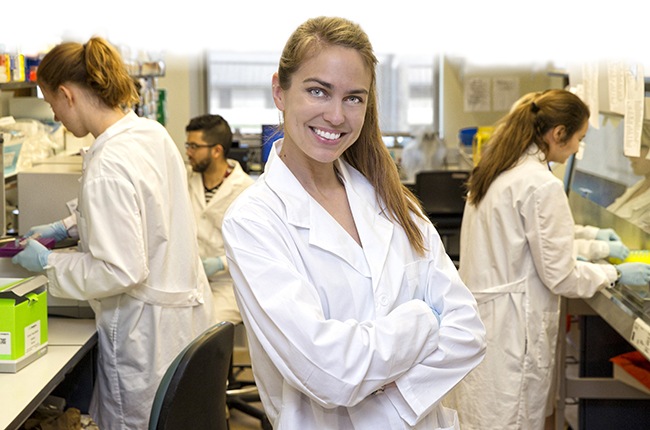 Sarah Hamer posing in her lab coat for the picture with her arms crossed