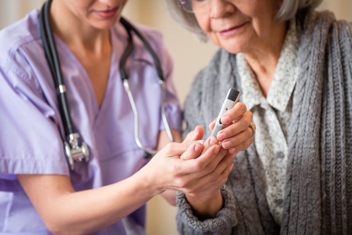Nurse giving blood sugar test to patient in home. (Getty Images)