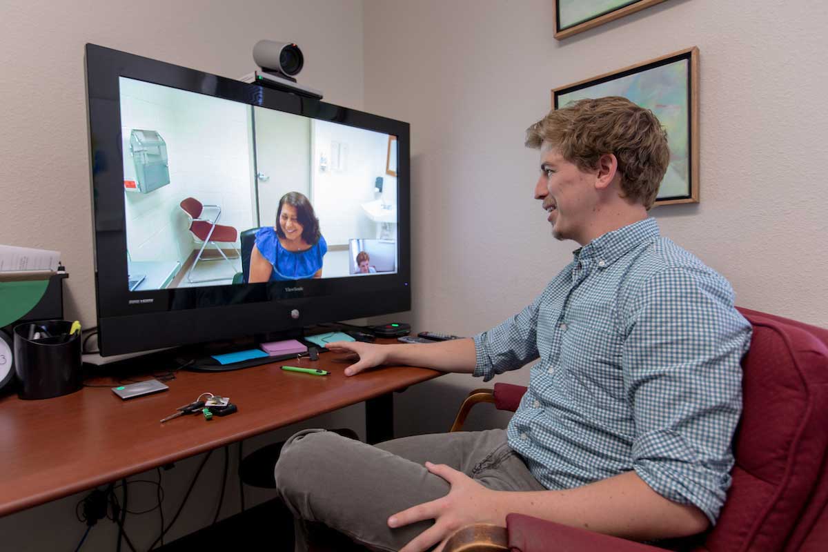 Donnie Kleine-Kracht sitting at his desk videoconferencing with a woman